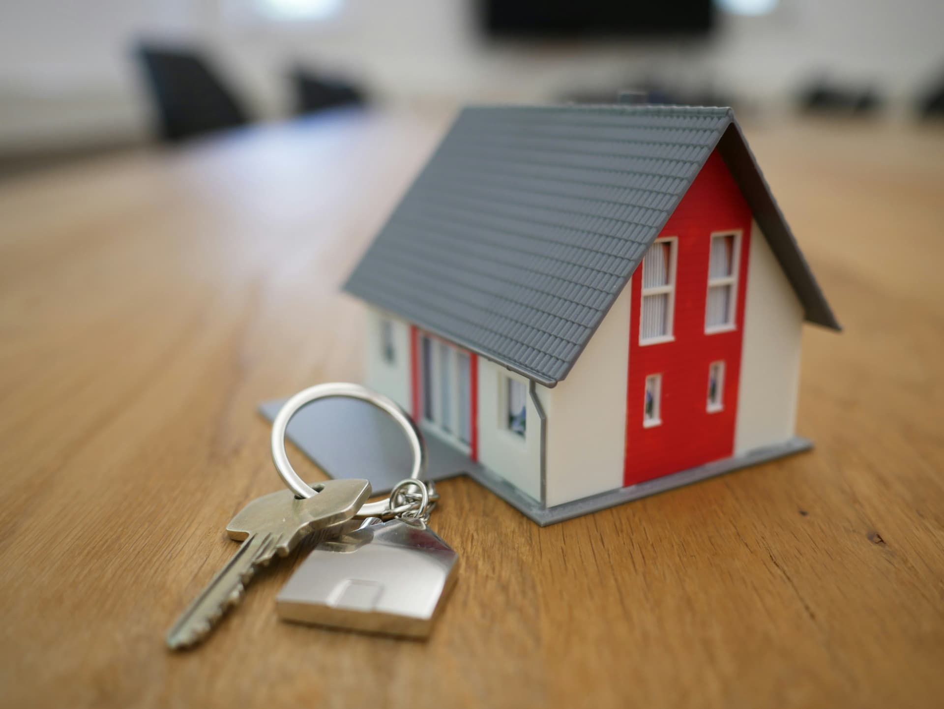 A person holding a set of house keys with a small house-shaped keychain.