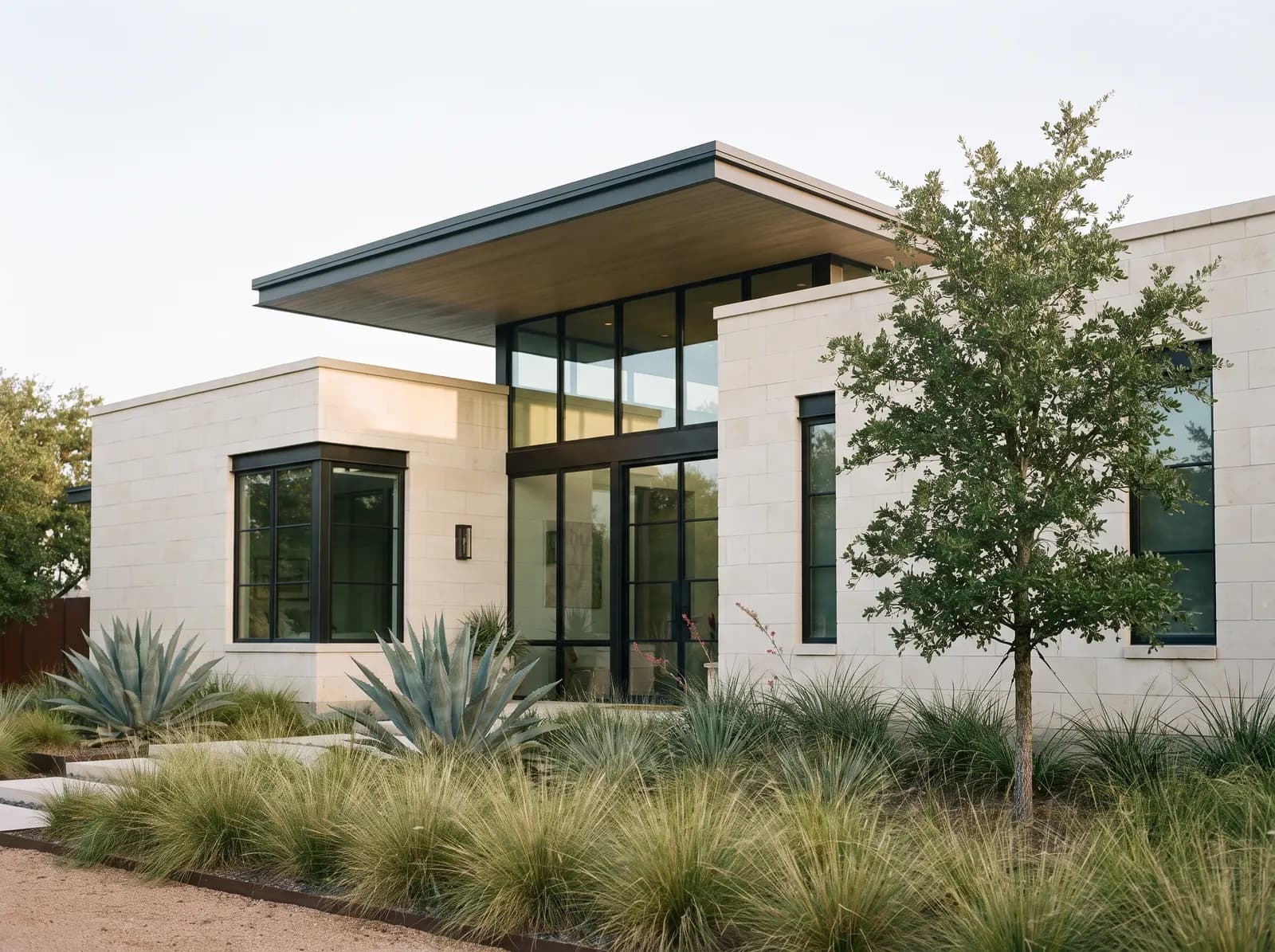 Casa contemporánea de piedra caliza y ventanales con jardín de plantas nativas