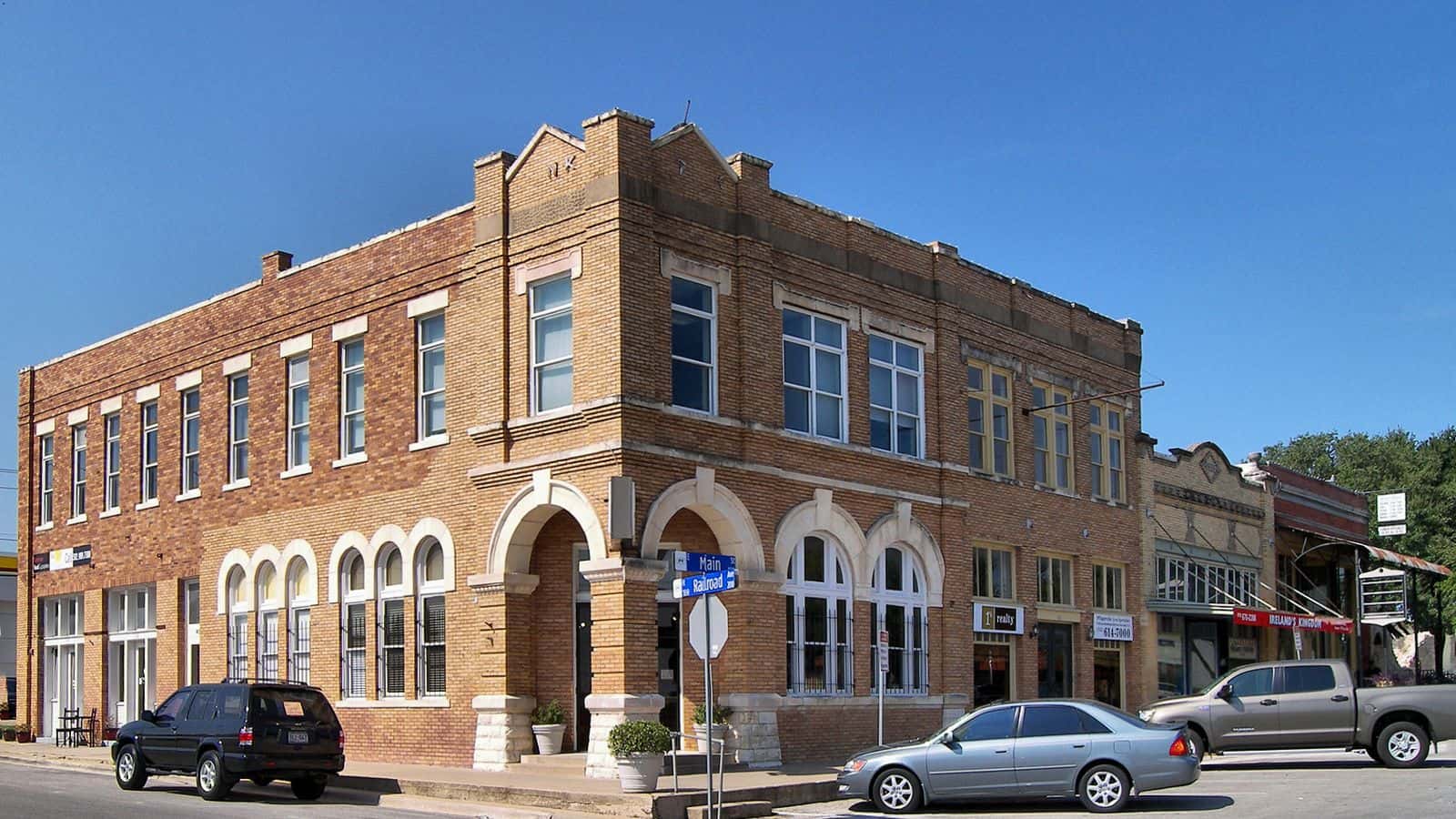 Edificio histórico de ladrillo de dos pisos con arcos, en una esquina del distrito histórico de East Main Street en Pflugerville